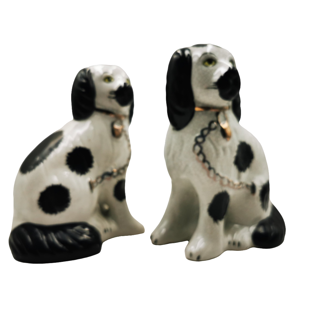 Two ceramic dog figurines with black and white spots on a white background